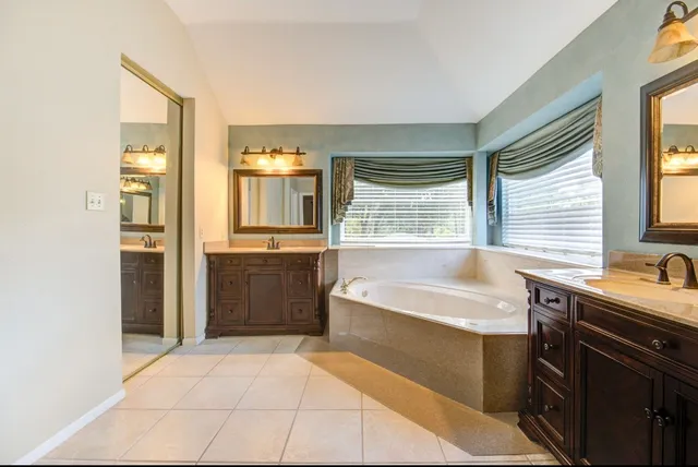 a spacious bathroom with a tub sink shower and mirror