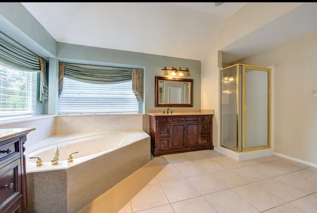 a bathroom with a tub a double vanity sink a mirror and a shower