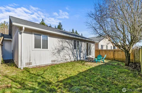 a view of a backyard with chairs potted plants and wooden fence