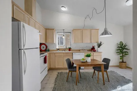 a kitchen with granite countertop a white refrigerator a dining table and chairs with wooden floor