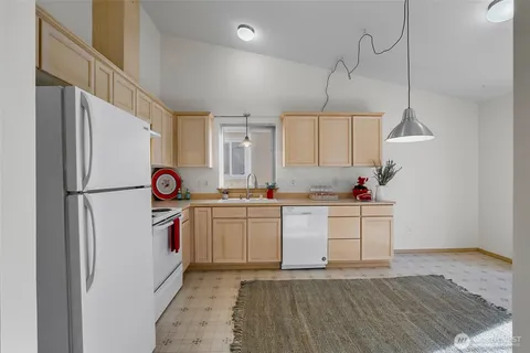 a kitchen with granite countertop a refrigerator a sink and white cabinets