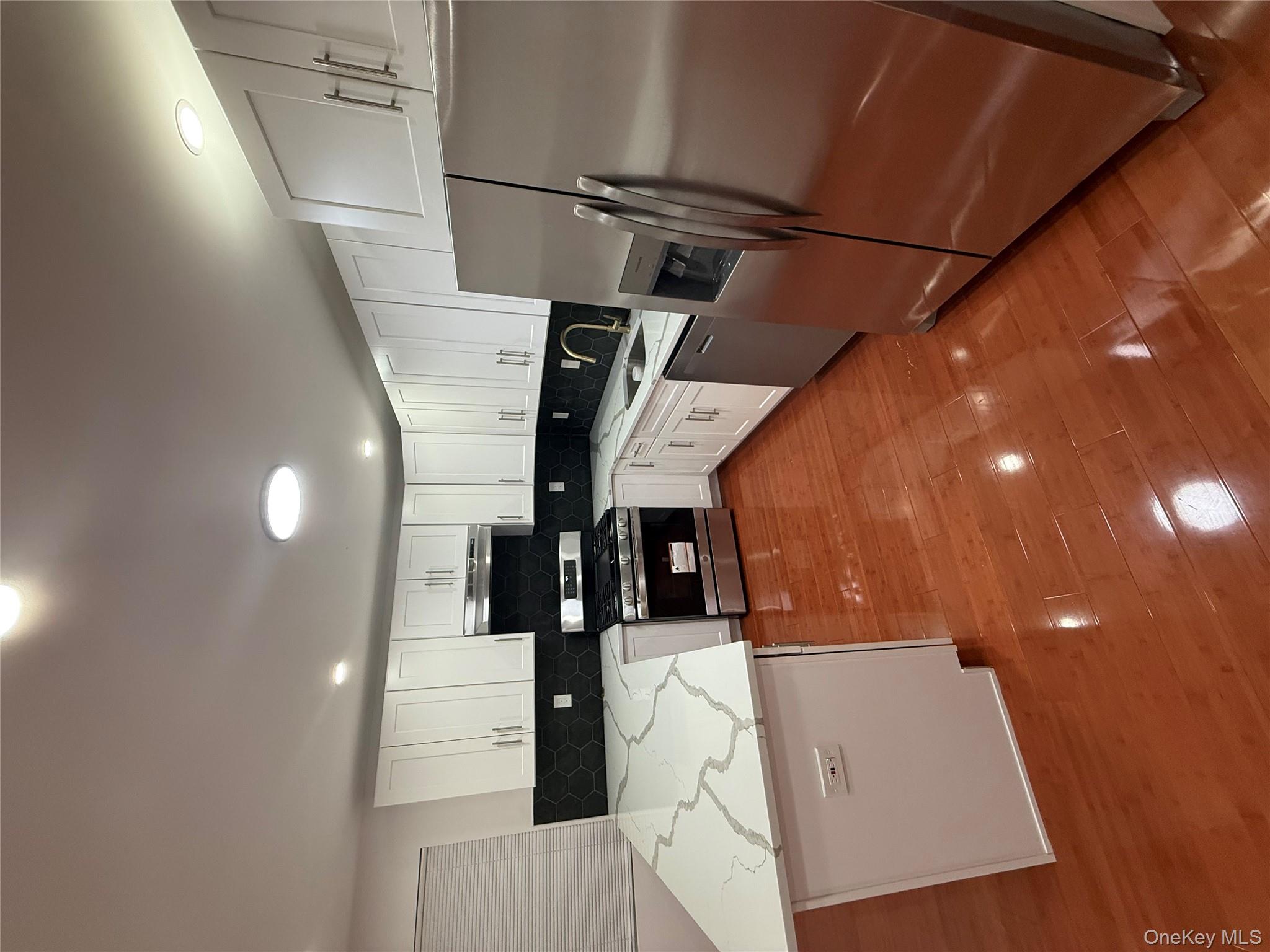 107-13 220th Street Queens, NY 11429 - Photo 2 of 10 a kitchen with stainless steel appliances granite countertop a stove top oven a sink dishwasher and white cabinets