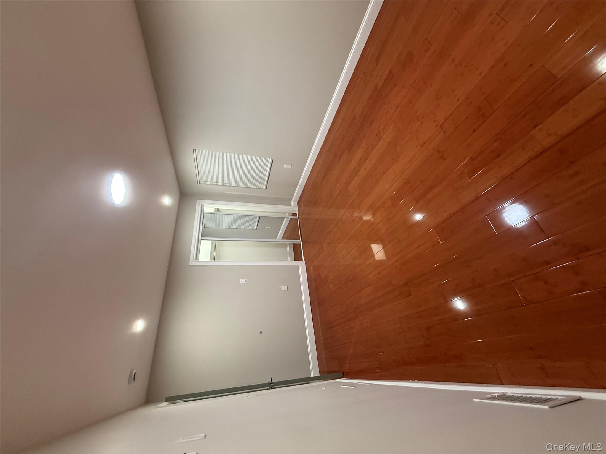 107-13 220th Street Queens, NY 11429 - Photo 7 of 10 an empty room with wooden floor and windows in it