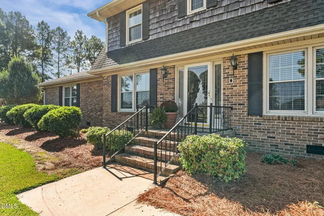 a view of a brick house with large windows and a table and chairs