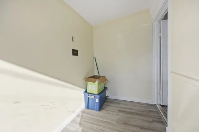 a view of an empty room with wooden floor fireplace and a kitchen