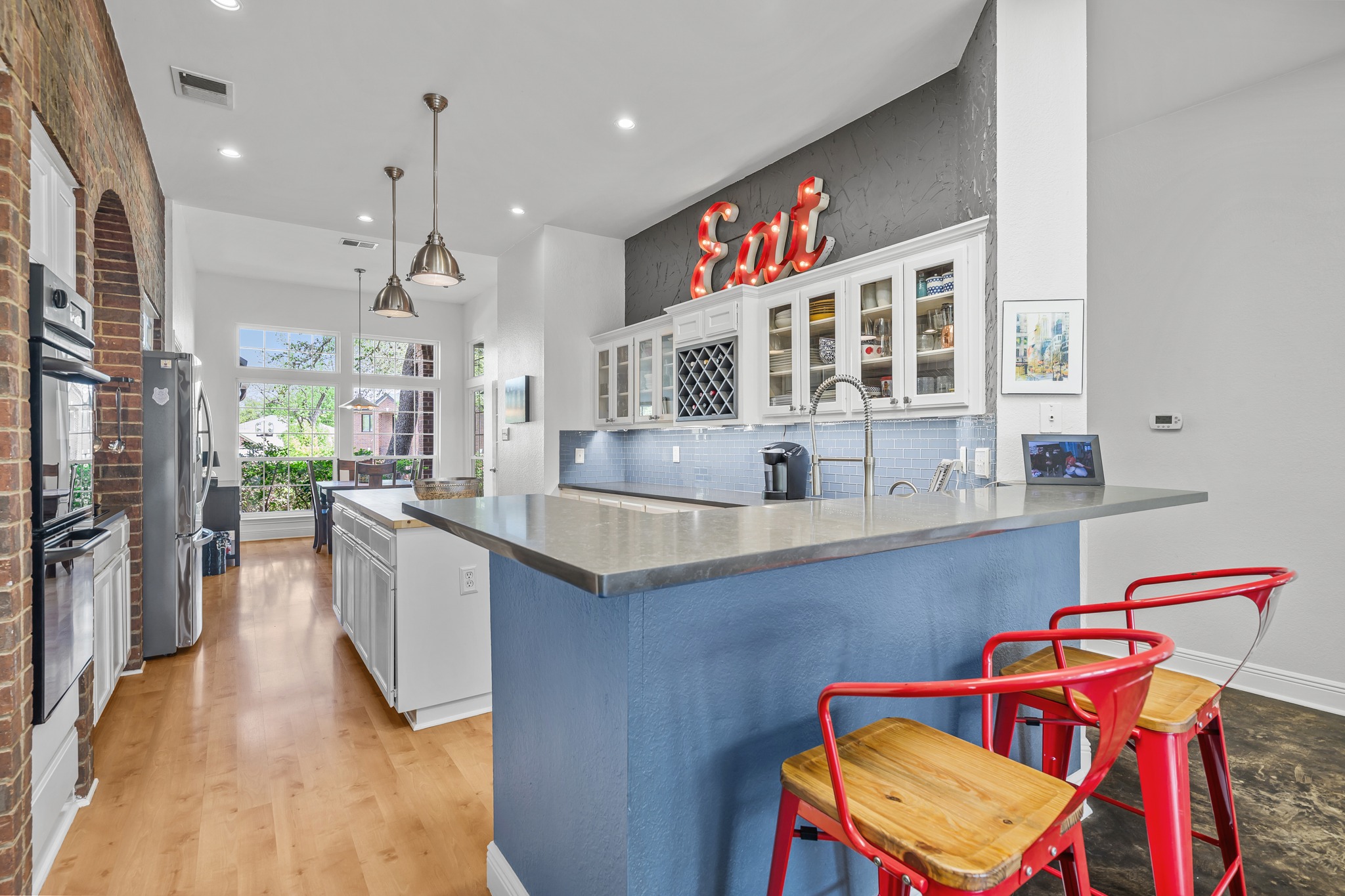 4801 Counts Cove Austin, TX 78749 - Photo 7 of 40 Kitchen featuring glass fronted cabinets, a breakfast bar, a kitchen island, a peninsula, and hanging light fixtures