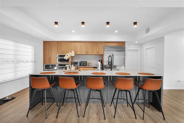 a dining hall with stainless steel appliances granite countertop a sink dishwasher and a refrigerator with wooden floor