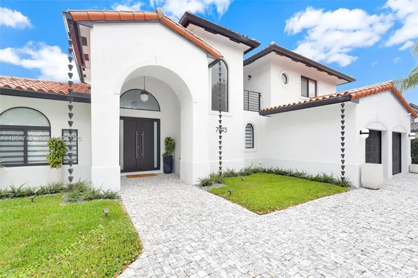 a view of a grey house with small yard and plants