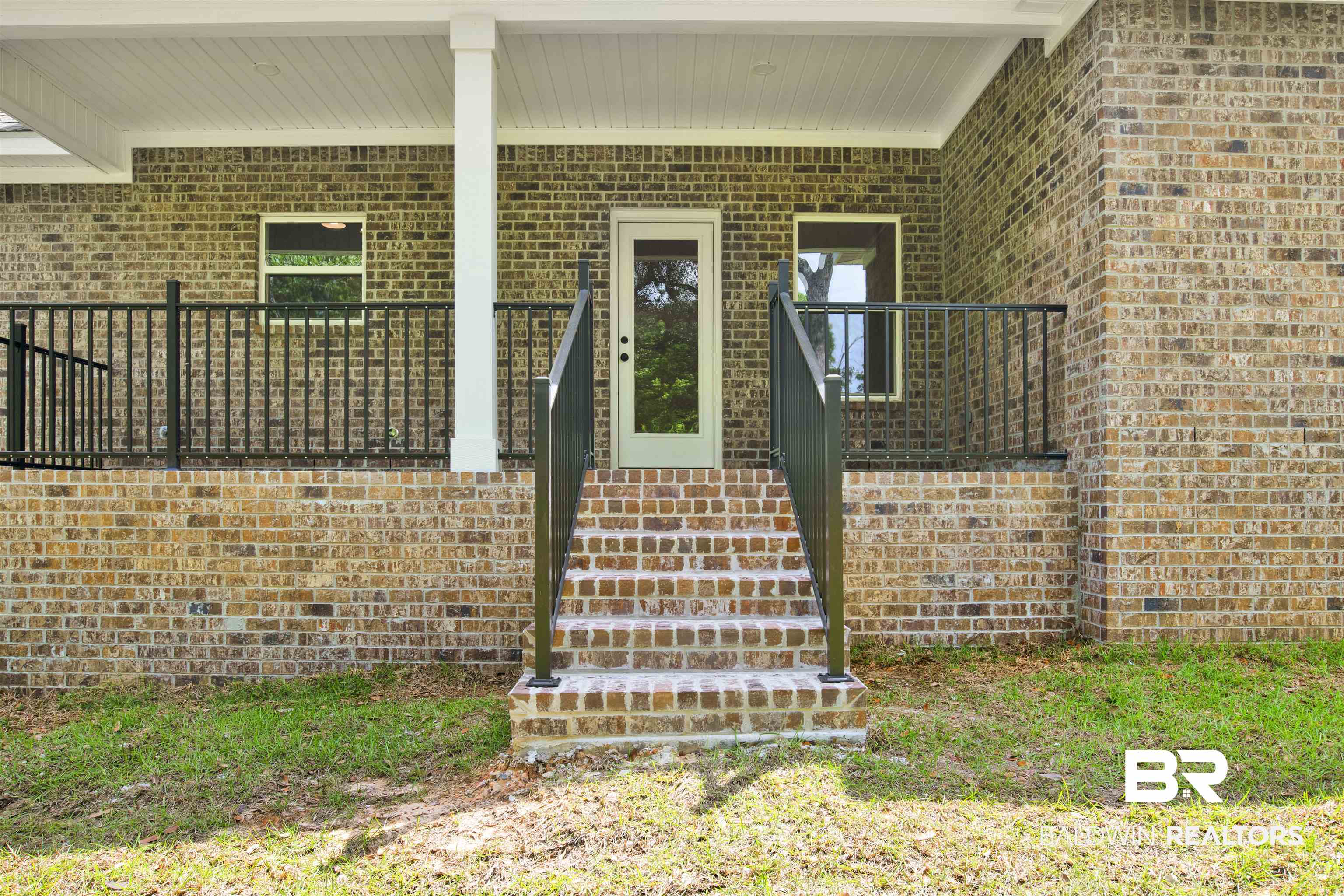 8760 Floyd Crabtree Way Semmes, AL 36575 - Photo 27 of 34 Brick exterior with a covered porch featuring white support columns and a white soffit ceiling