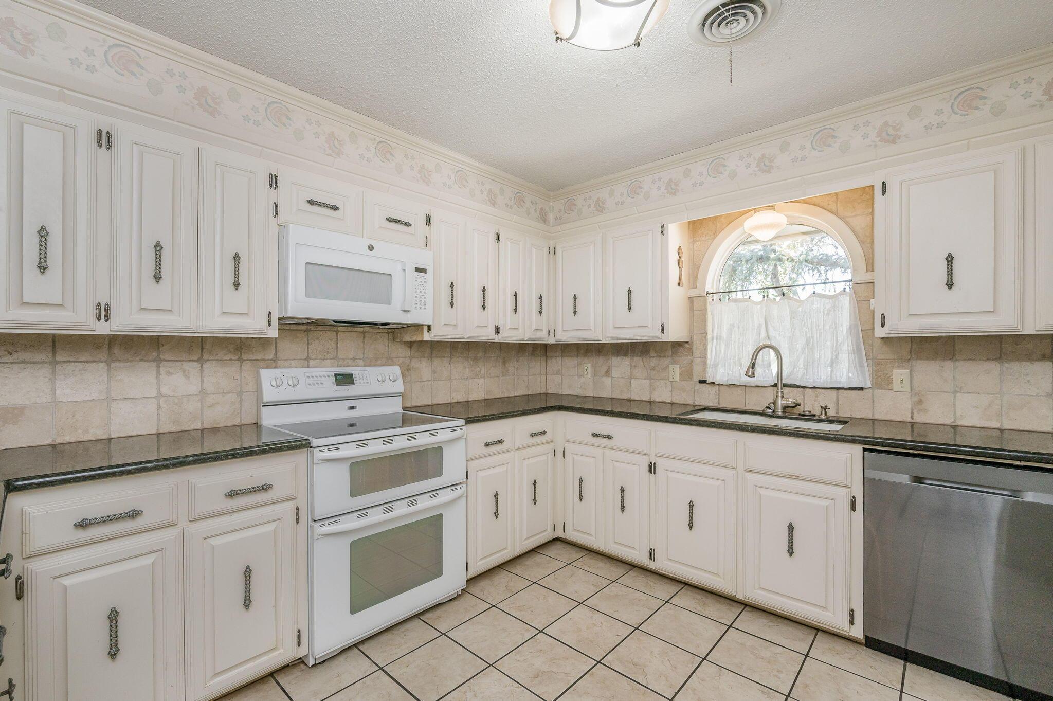 1102 Creekmere Drive Canyon, TX 79015 - Photo 6 of 29 a kitchen with granite countertop white cabinets white appliances and a sink