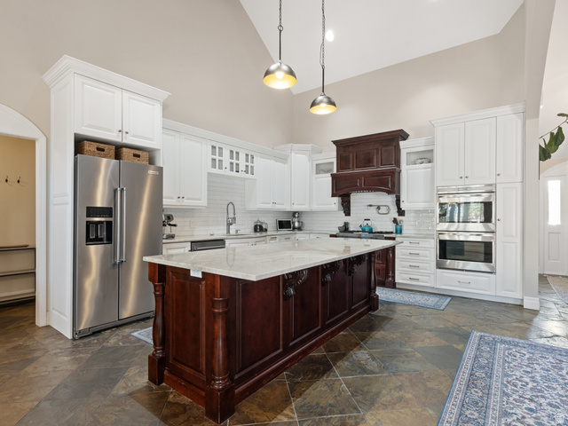 13357 Trail Rider Circle Draper, UT 84020 - Photo 10 of 70 Expansive kitchen featuring a large central island with a light-toned countertop, white cabinetry, integrated stainless steel appliances, a decorative dark wood range hood, and slate flooring