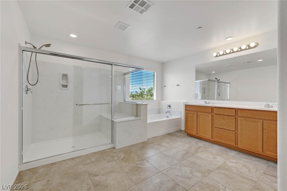 155 Fulgora Street Henderson, NV 89074 - Photo 11 of 30 A spacious primary bathroom with a separate soaking tub and a generous walk-in shower.