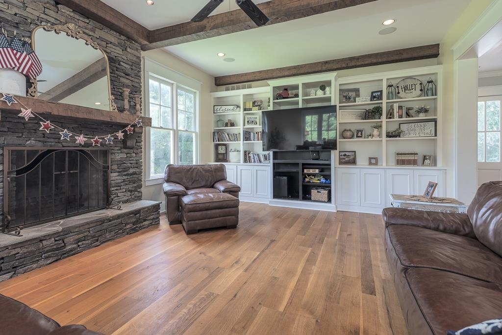 1915 Teague Store Road Somerville, TN 38068 - Photo 23 of 38 Spacious living area featuring a stone fireplace with a wood mantle, extensive built-in shelving, durable wood-finish flooring, and exposed ceiling beams