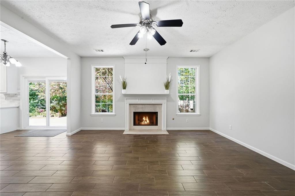 3318 Ridgemill Circle Dacula, GA 30019 - Photo 61 of 106 an empty room with windows a fireplace a ceiling fan and wooden floor