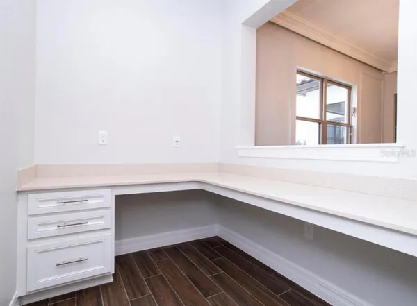 an empty room with a chandelier fan and wooden floor