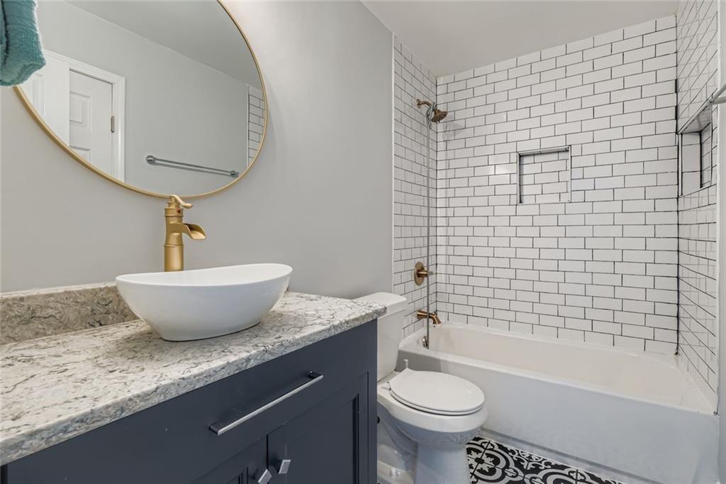 677 Ira Street Southwest Atlanta, GA 30310 - Photo 15 of 28 a bathroom with a granite countertop sink a toilet a mirror and bathtub