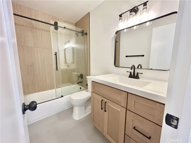 a bathroom with a sink a toilet a mirror and shower