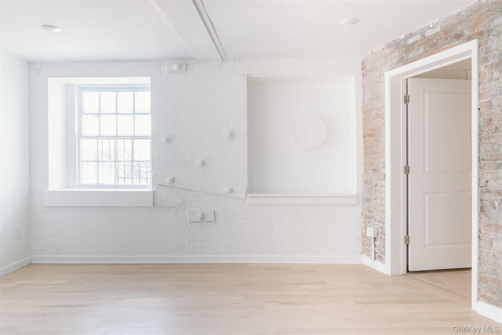 155 River Street, Unit BA Troy, NY 12180 - Photo 2 of 26 Spare room featuring brick wall and light wood-style floors