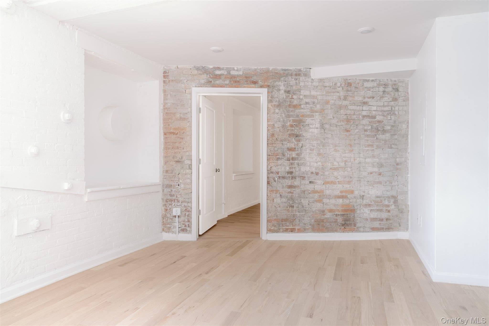 155 River Street, Unit BA Troy, NY 12180 - Photo 5 of 26 Empty room with brick wall and wood finished floors