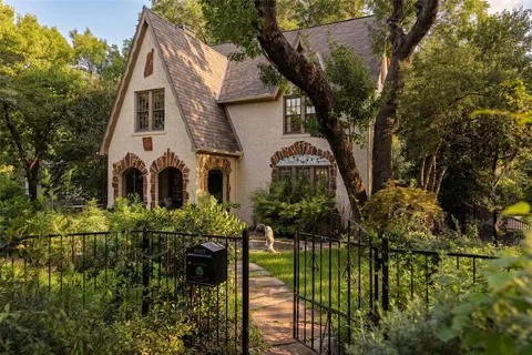 a view of a white house next to a yard with potted plants
