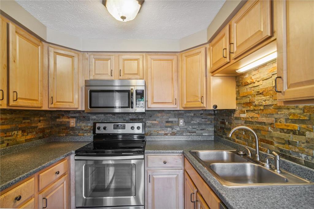 310 Ridge Point Circle Bridgeville, PA 15017 - Photo 10 of 24 a kitchen with stainless steel appliances granite countertop a sink a stove and a microwave