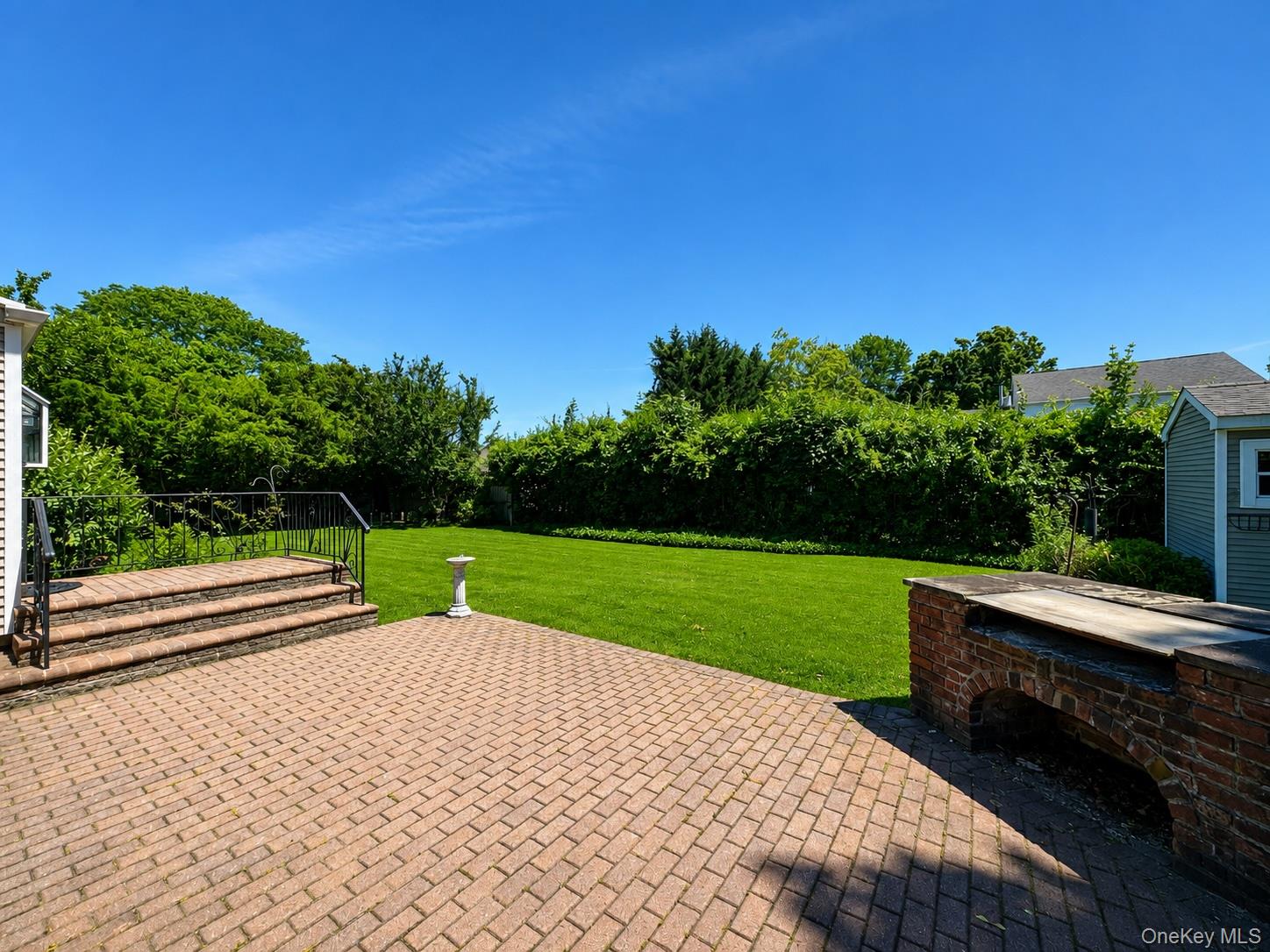 16 Clay Pitts Road Greenlawn, NY 11740 - Photo 21 of 25 Expansive backyard featuring a large brick paver patio, a built-in brick outdoor cooking station, lush green lawn, and mature perimeter trees