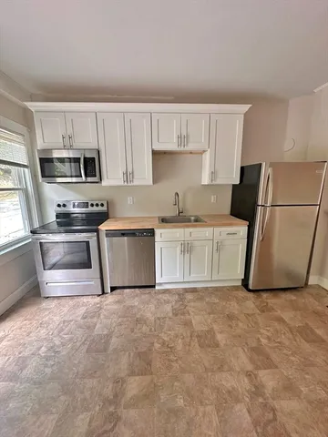 a kitchen with stainless steel appliances granite countertop a sink a stove a refrigerator with white cabinets