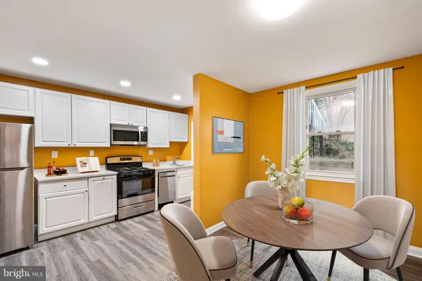 a kitchen with stainless steel appliances granite countertop a kitchen island hardwood floor sink and dining table