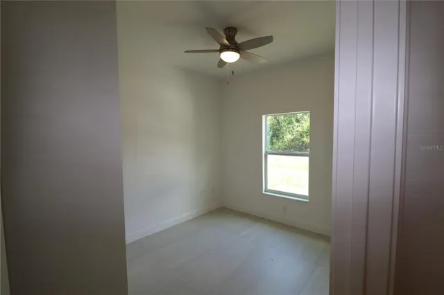 an empty room with window and ceiling fan