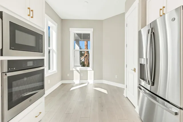 a view of kitchen with stainless steel appliances wooden floor and stove