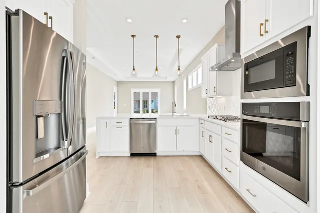 a kitchen with stainless steel appliances white cabinets and wooden floors