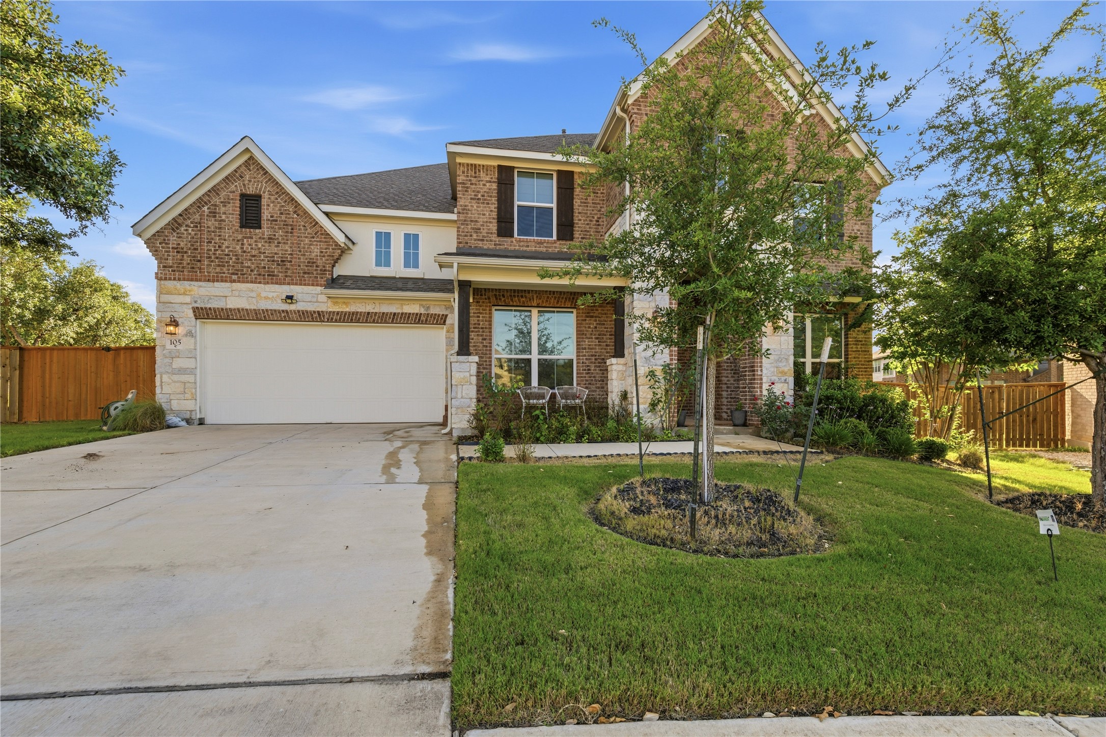 105 Autumn Oak Way Georgetown, TX 78628 - Photo 1 of 40 Two-story residence featuring a brick and stone facade, a two-car garage, established front landscaping, a covered entryway, and multiple windows with dark shutters
