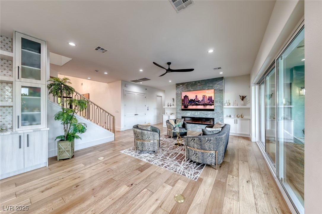 2309 Prometheus Court Henderson, NV 89074 - Photo 11 of 70 Living room featuring light wood-style floors, stairs, a tiled fireplace, ceiling fan, and recessed lighting