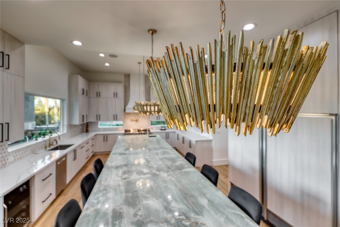 2309 Prometheus Court Henderson, NV 89074 - Photo 19 of 70 Kitchen with a breakfast bar area, white cabinetry, light stone counters, pendant lighting, and wine cooler