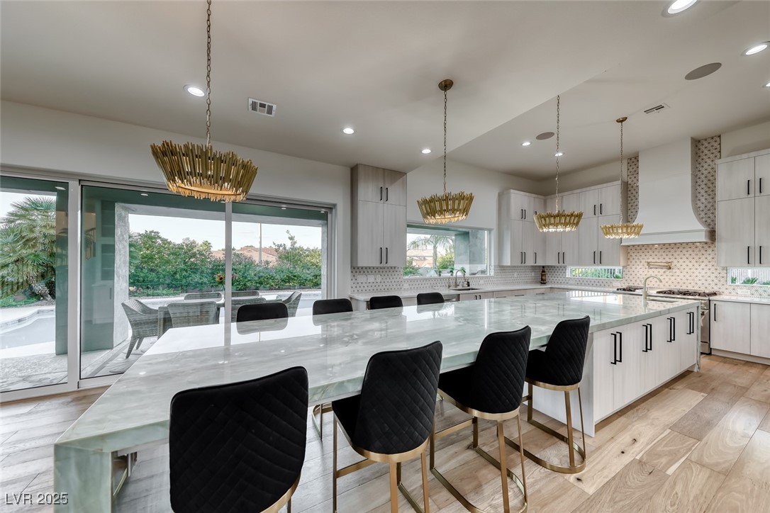 2309 Prometheus Court Henderson, NV 89074 - Photo 22 of 70 Kitchen with a breakfast bar, light wood-type flooring, light stone countertops, decorative backsplash, and a large island with sink