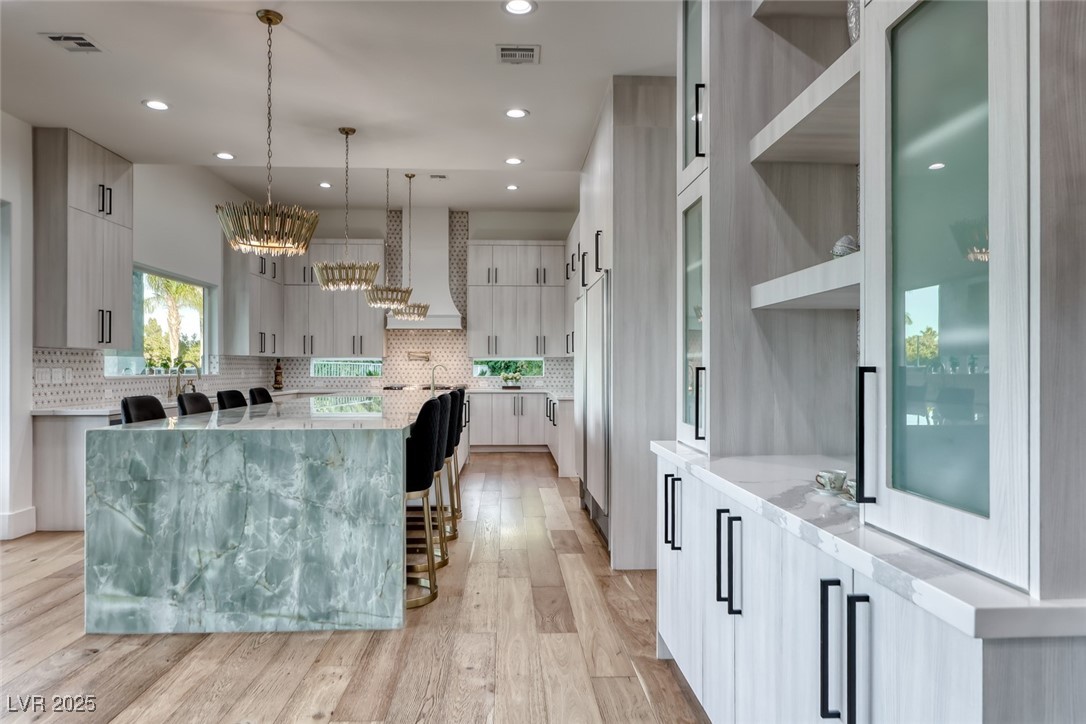 2309 Prometheus Court Henderson, NV 89074 - Photo 24 of 70 Kitchen with light stone counters, pendant lighting, modern cabinets, a kitchen island with sink, and light wood finished floors