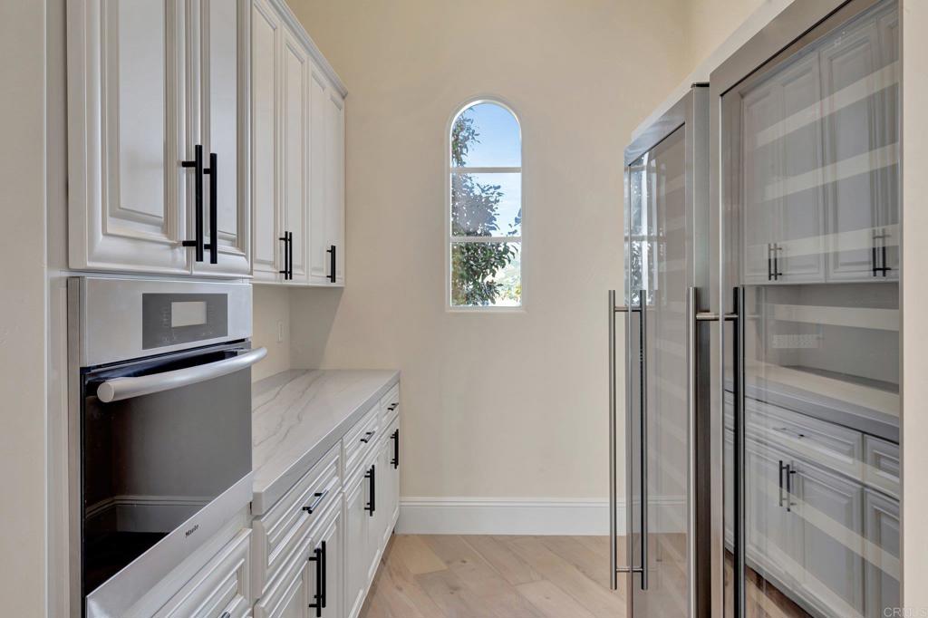 8025 La Milla Rancho Santa Fe, CA 92067 - Photo 10 of 51 a kitchen with white cabinets and a refrigerator