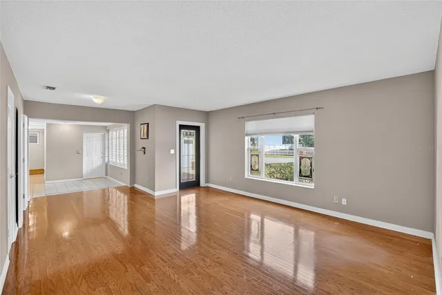 a view of an empty room with window and wooden floor