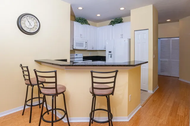 a kitchen with stainless steel appliances a table chairs in it and wooden floors