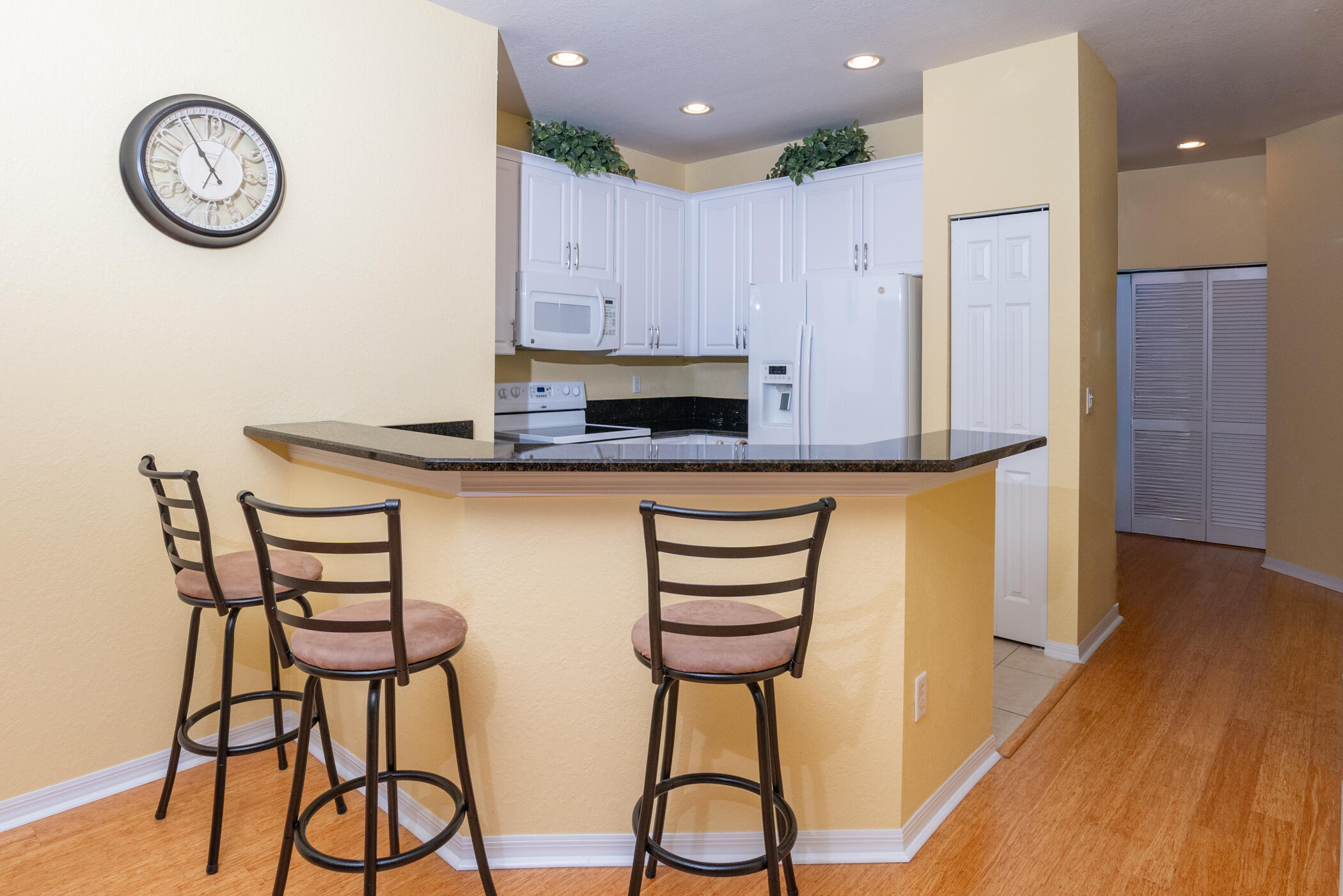 1600 Southeast Sheffield Terrace, Unit 201 Stuart, FL 34994 - Photo 13 of 28 a kitchen with stainless steel appliances a table chairs in it and wooden floors