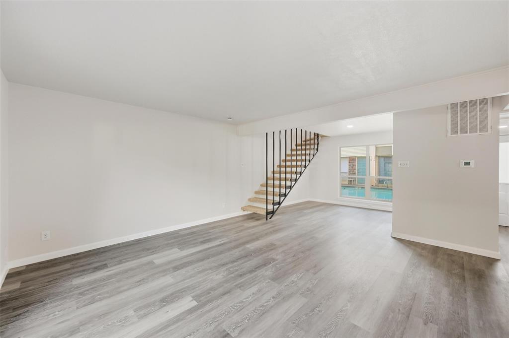2702 Douglas Avenue, Unit 121 Dallas, TX 75219 - Photo 18 of 34 a view of an empty room with wooden floor and stairs