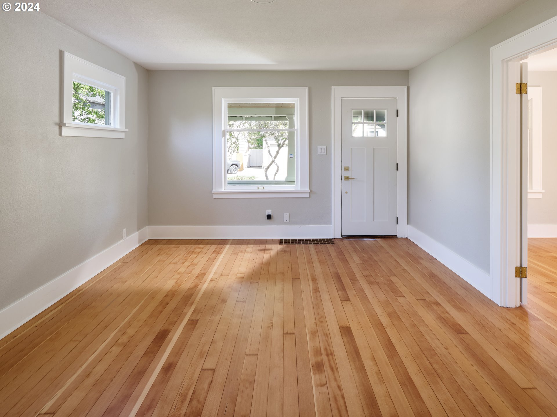 10342 Southeast Ramona Street Portland, OR 97266 - Photo 3 of 17 an empty room with wooden floor and windows