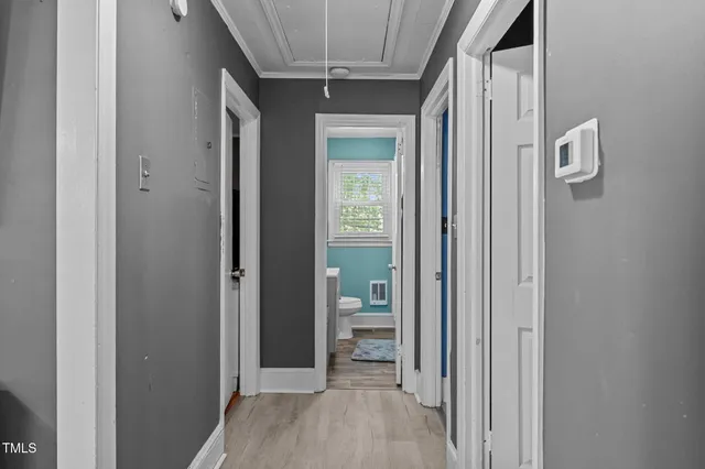 a view of a hallway with wooden floor and a bathroom
