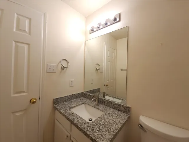 a bathroom with a granite countertop sink toilet and mirror