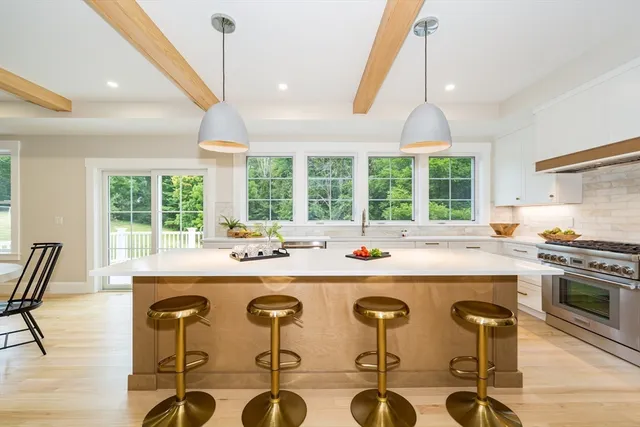 a kitchen with stainless steel appliances granite countertop a stove a sink a kitchen island with chairs and wooden cabinets