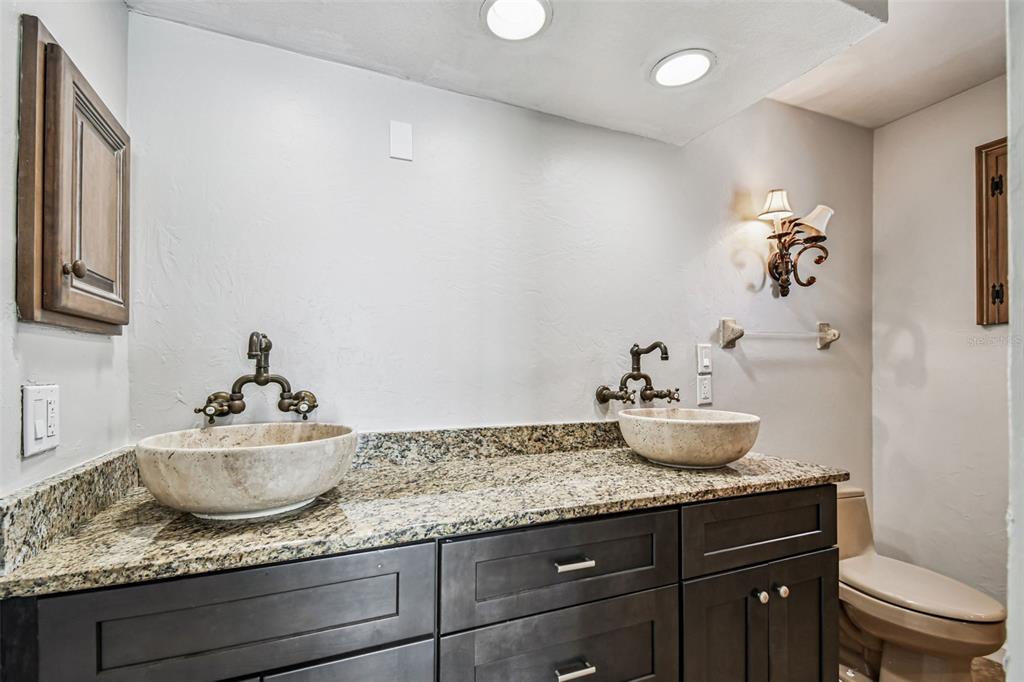 529 Johns Pass Avenue Madeira Beach, FL 33708 - Photo 30 of 100 a bathroom with a granite countertop sink a toilet and mirror