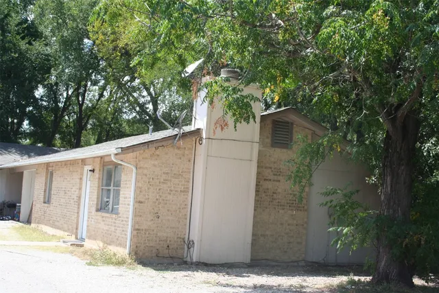 a side view of a house with a tree