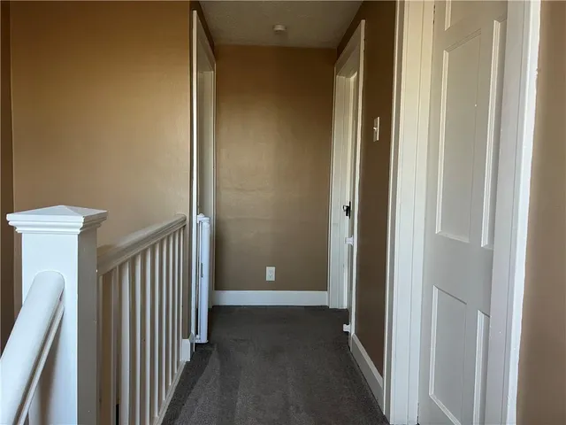 a view of a hallway with wooden floor and a door