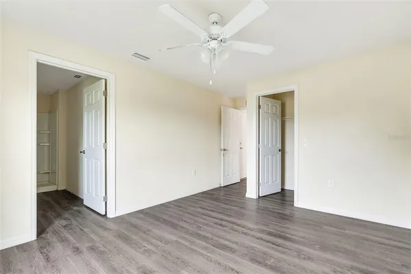 an empty room with wooden floor and a ceiling fan