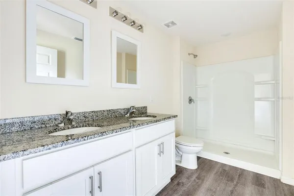 a bathroom with a granite countertop sink a toilet and shower